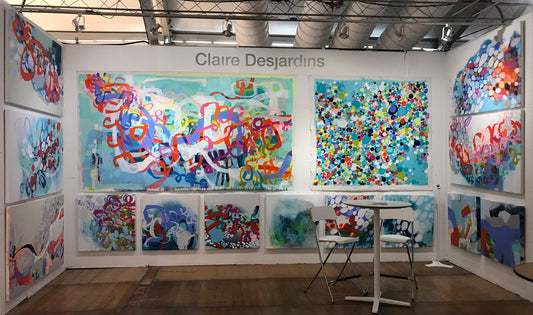 Abstract paintings hang in the booth of artist/painter Claire Desjardins, at art fair.