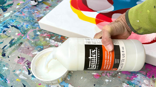 Artist Claire Desjardins pours varnish into a white cup, in her art studio.