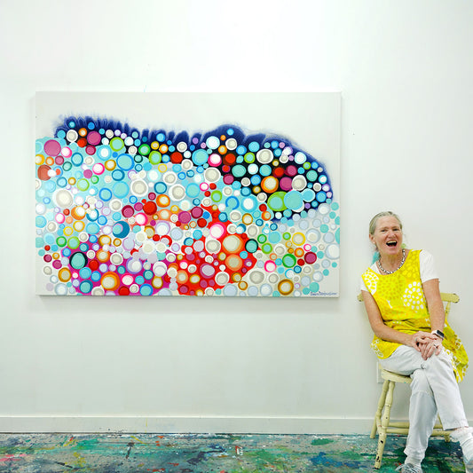Canadian abstract artist, Claire Desjardins, sitting next to her original artwork, Instinct for Hope.